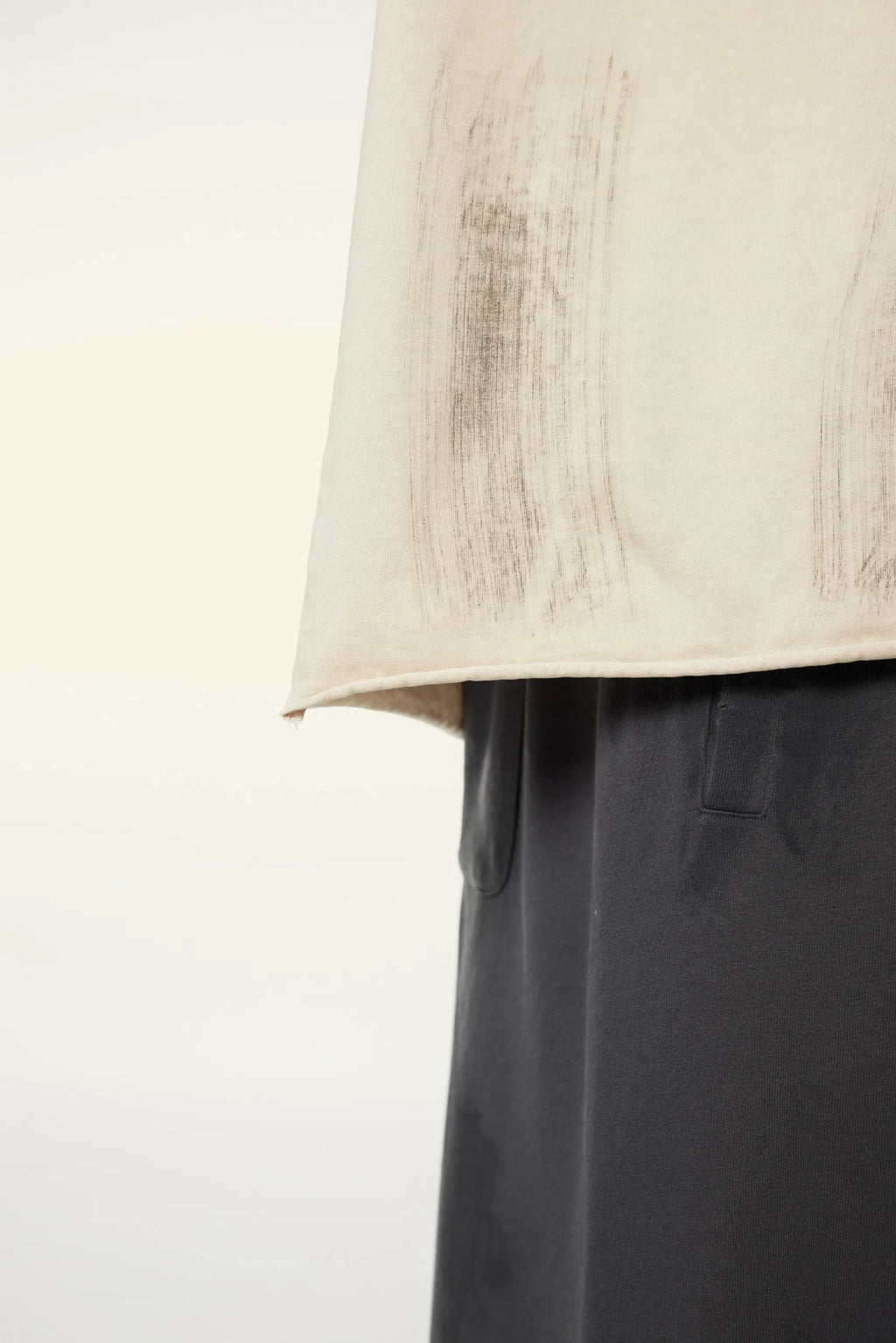 Close-up of a beige jacket and dark pants on a white background