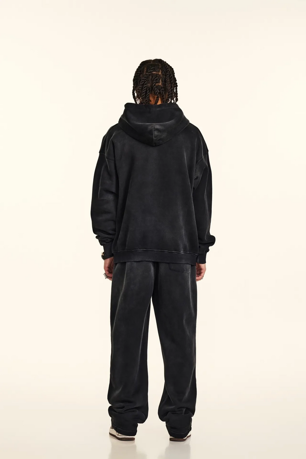 Person wearing a black hoodie and pants set on a white background