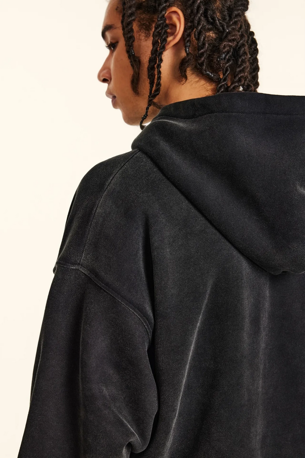 Person wearing a black hoodie from behind on a plain background