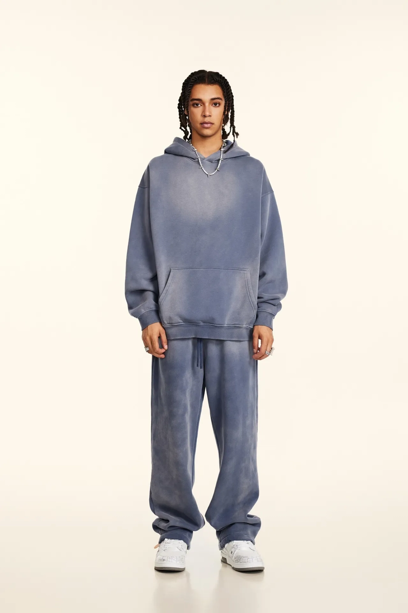 Person wearing a blue hoodie and pants set on a white background