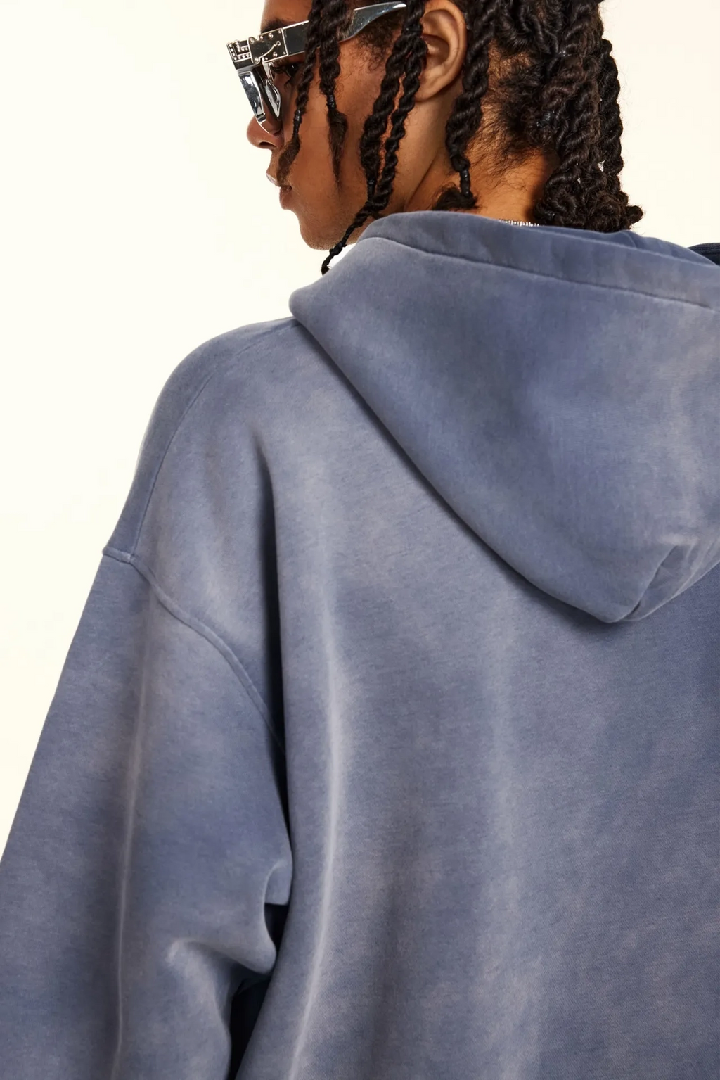 Person wearing a blue hoodie from behind with a neutral background