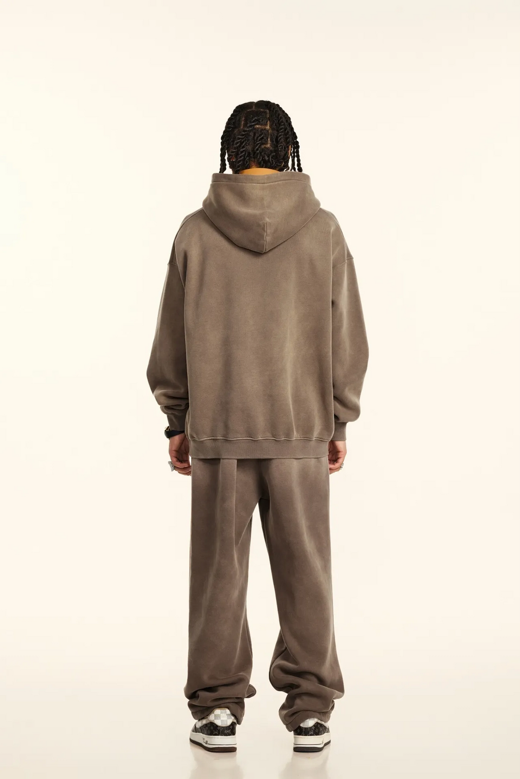Person wearing a brown hoodie and pants set on a white background
