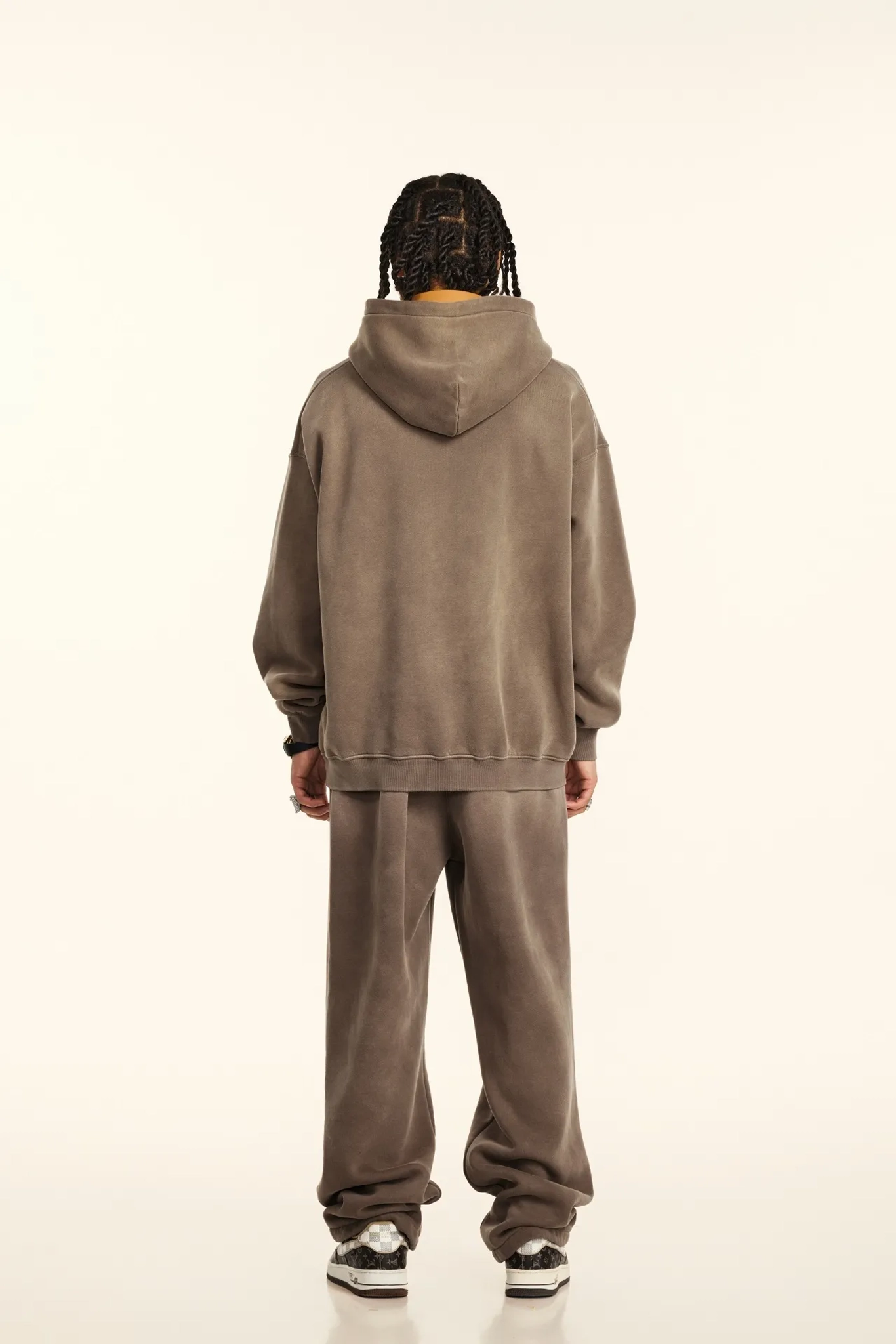 Person wearing a brown hoodie and pants set on a white background