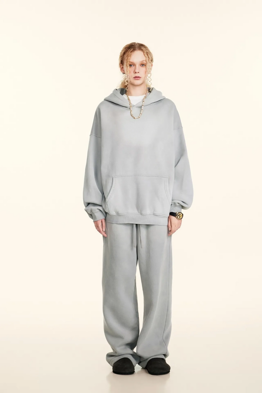 Person wearing a gray hoodie and pants on a white background