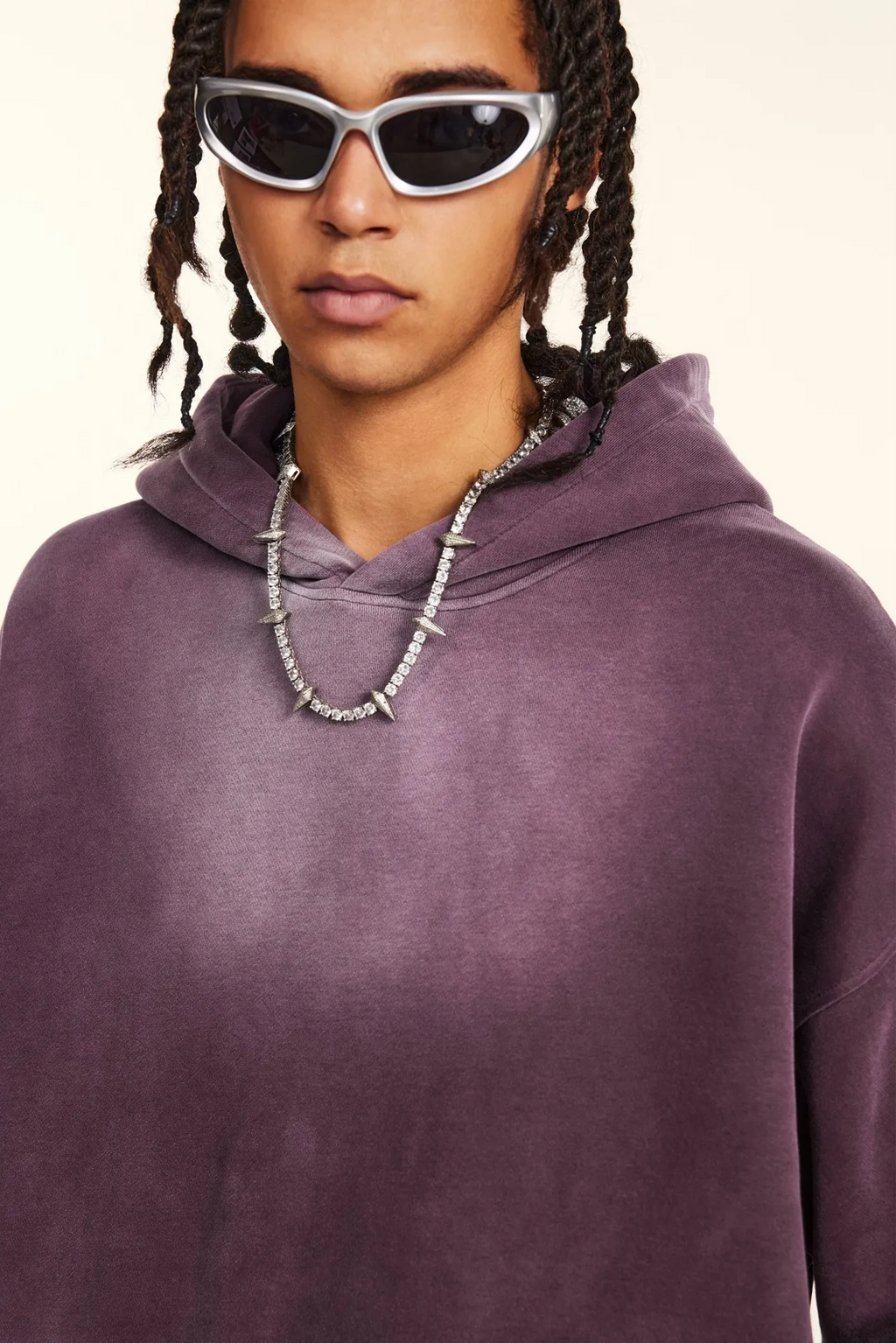 Person wearing a purple hoodie and sunglasses with a neutral background