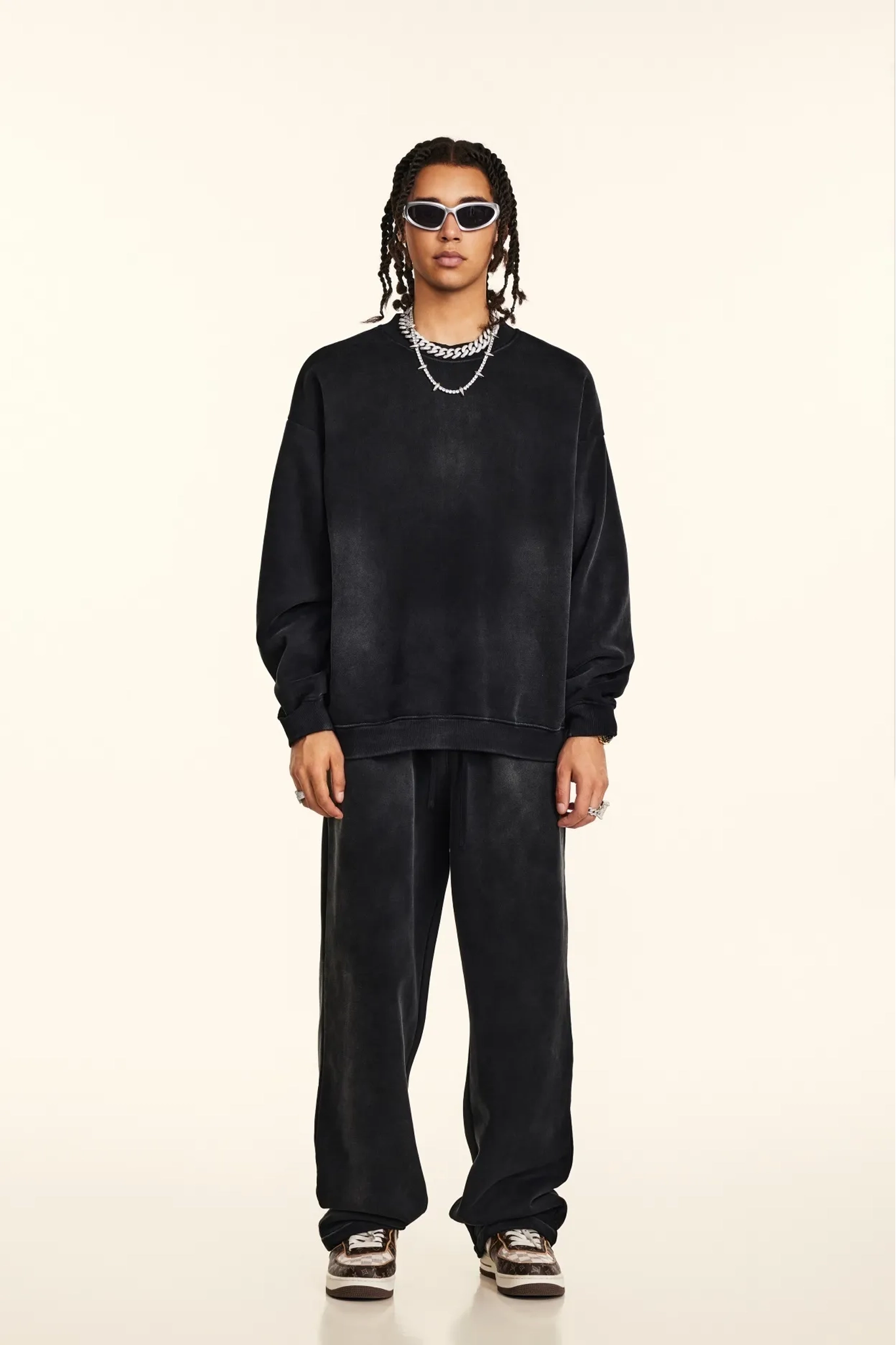 Person wearing a black outfit with sunglasses on a white background