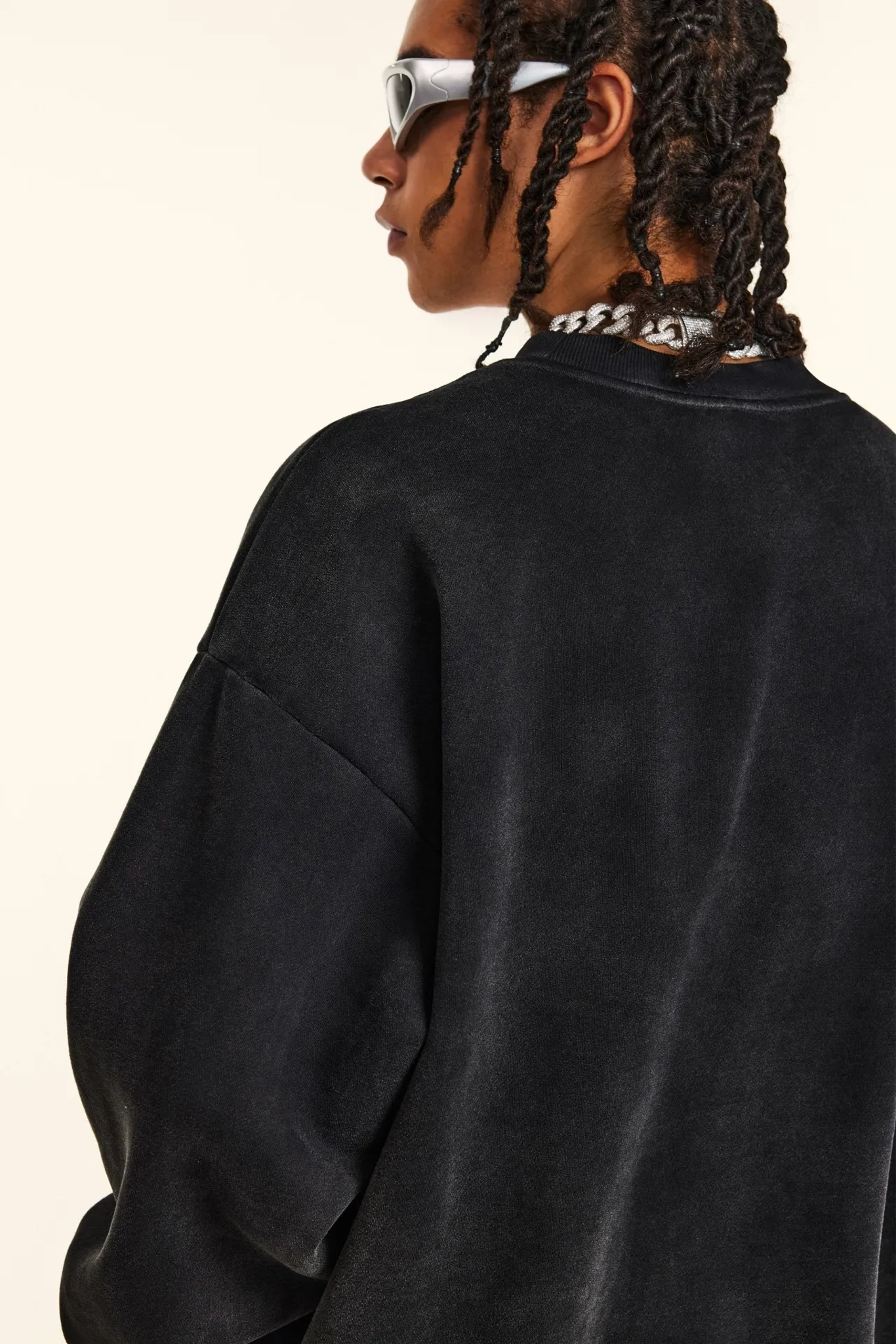 Person wearing a black oversized sweatshirt with a neutral background