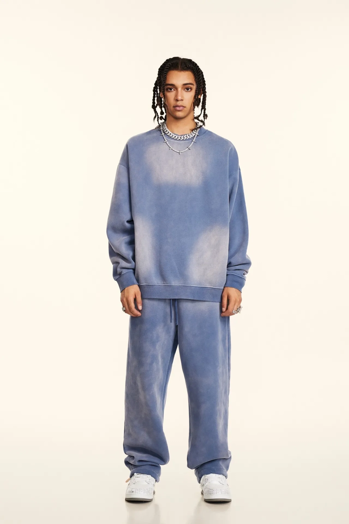 Person wearing a blue distressed sweatshirt and pants on a white background
