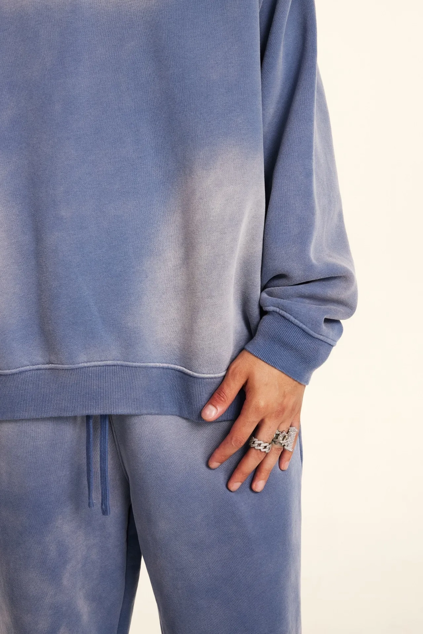 Blue sweatshirt and pants worn by a person on a white background