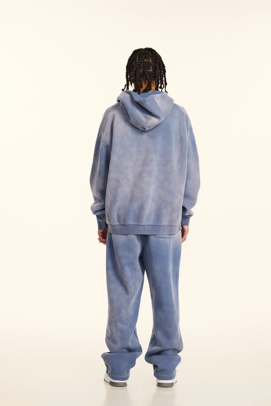 Person wearing a blue tie-dye hoodie and pants on a white background