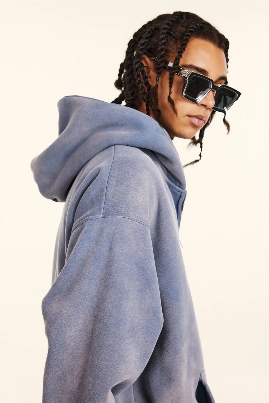 Person wearing a light blue hoodie and sunglasses on a white background