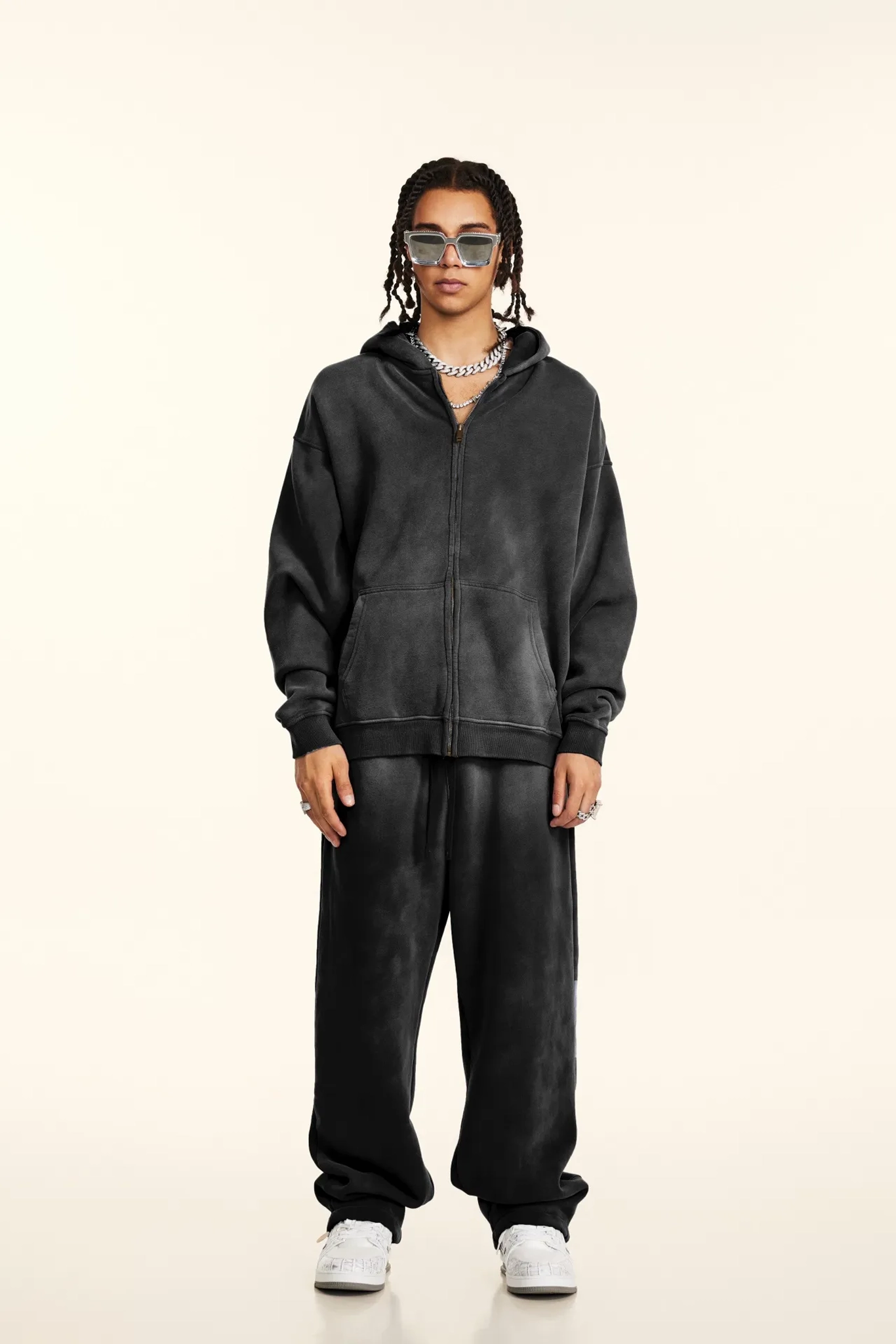 Person wearing a dark gray hoodie and pants on a white background