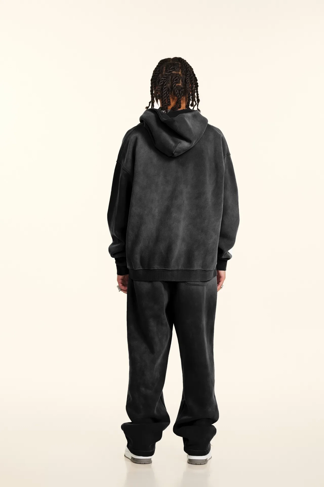 Person wearing a dark gray hoodie and pants on a white background