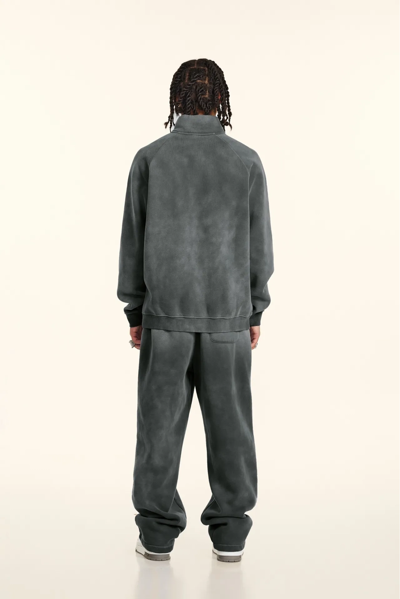 Person wearing a gray tracksuit on a white background