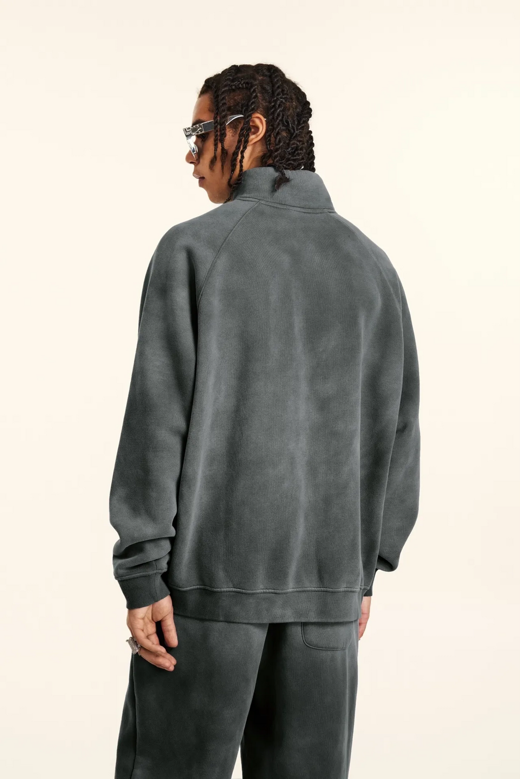 Person wearing a gray tracksuit from behind on a beige background