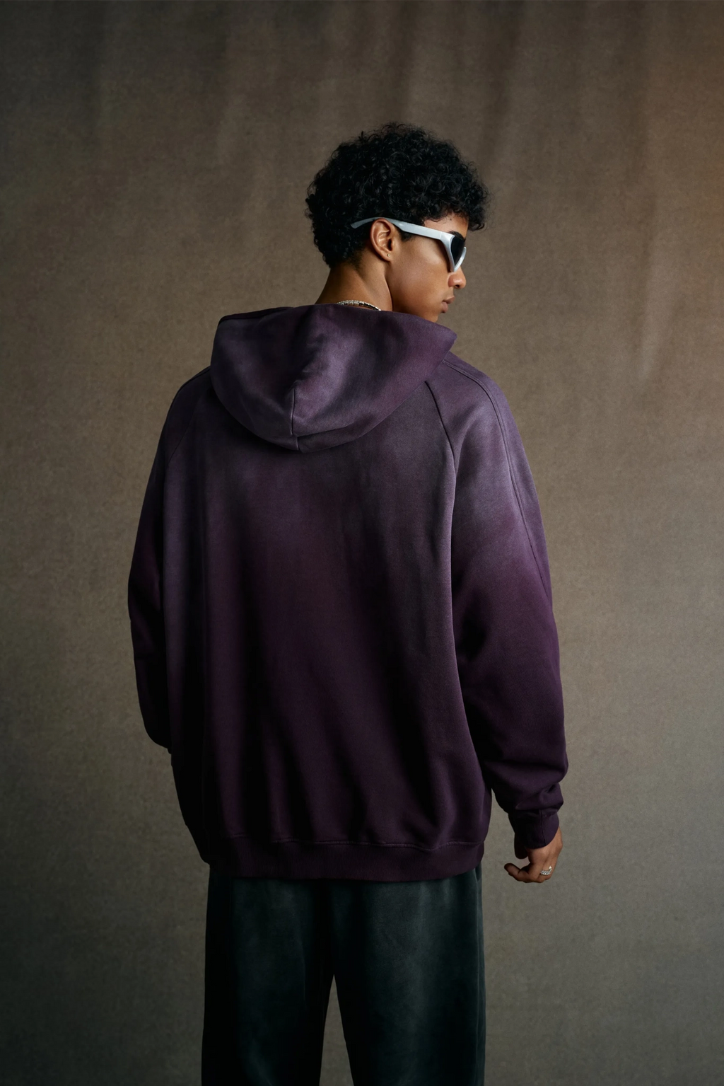 Person wearing a purple hoodie from behind against a plain background