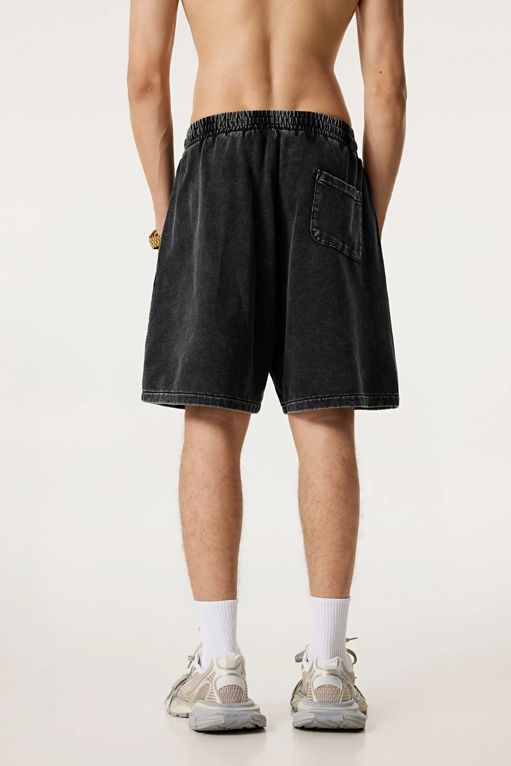 Person wearing black shorts on a plain background