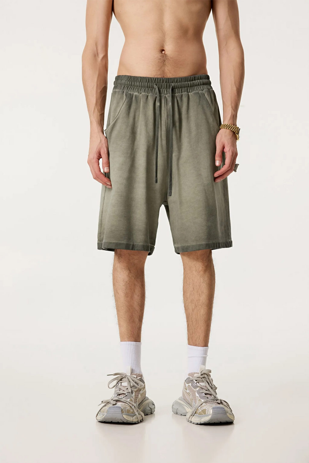Person wearing olive green shorts on a white background