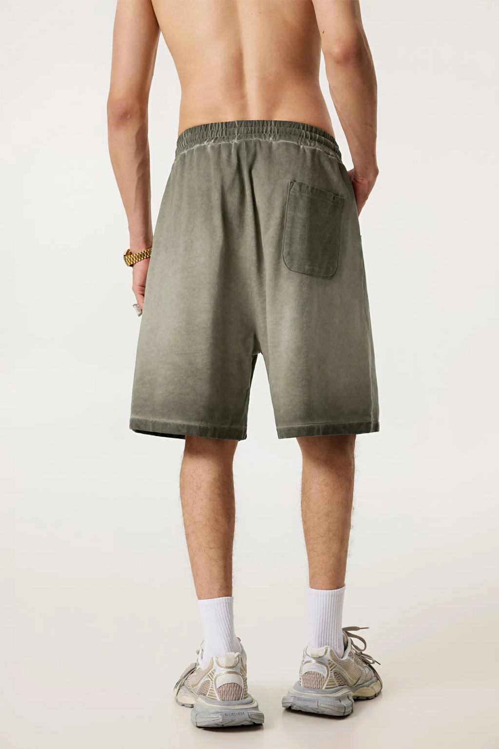 Person wearing olive green shorts on a plain background