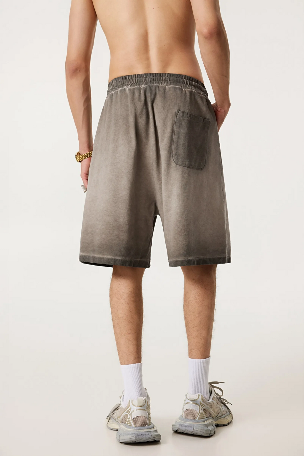 Person wearing brown shorts on a plain background