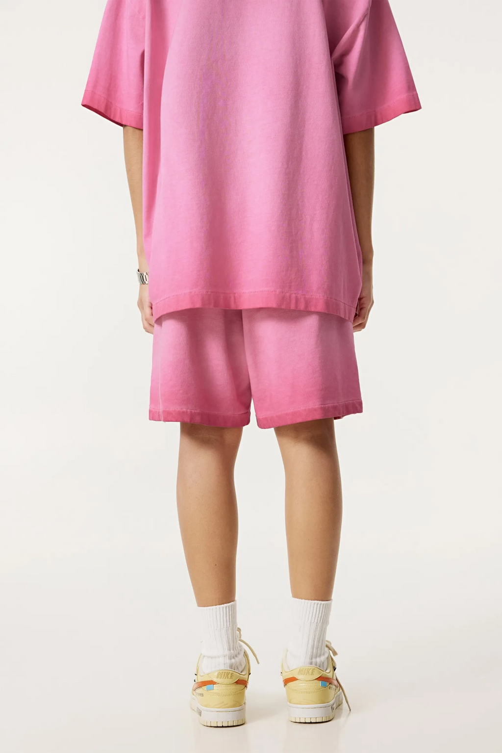 Person wearing a pink outfit with shorts on a white background