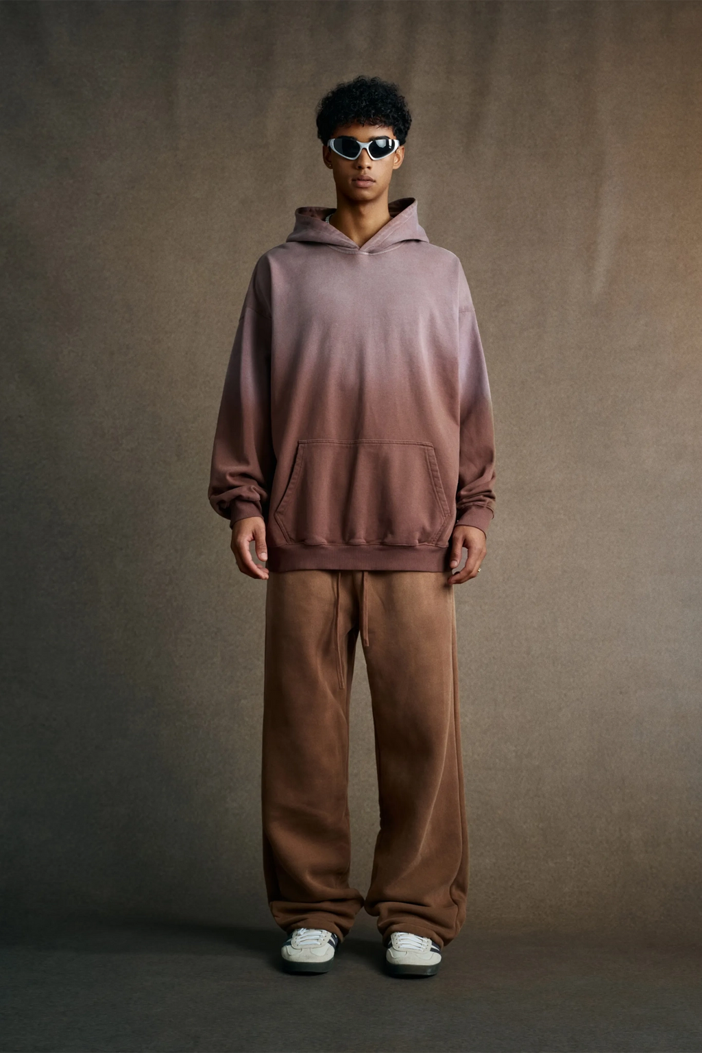 Person wearing a gradient hoodie and brown pants against a plain background