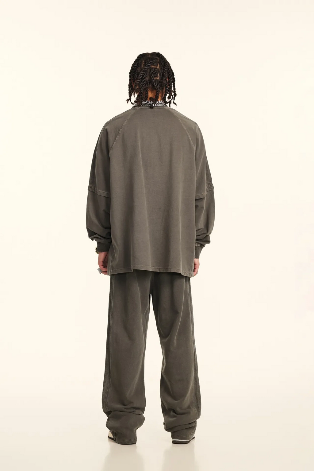 Person wearing a gray tracksuit from behind on a white background