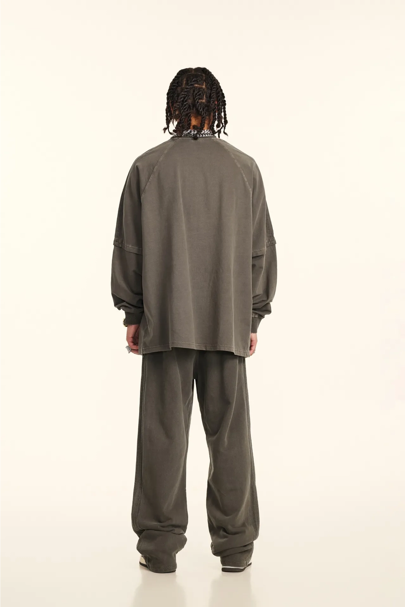 Person wearing a gray tracksuit from behind on a white background
