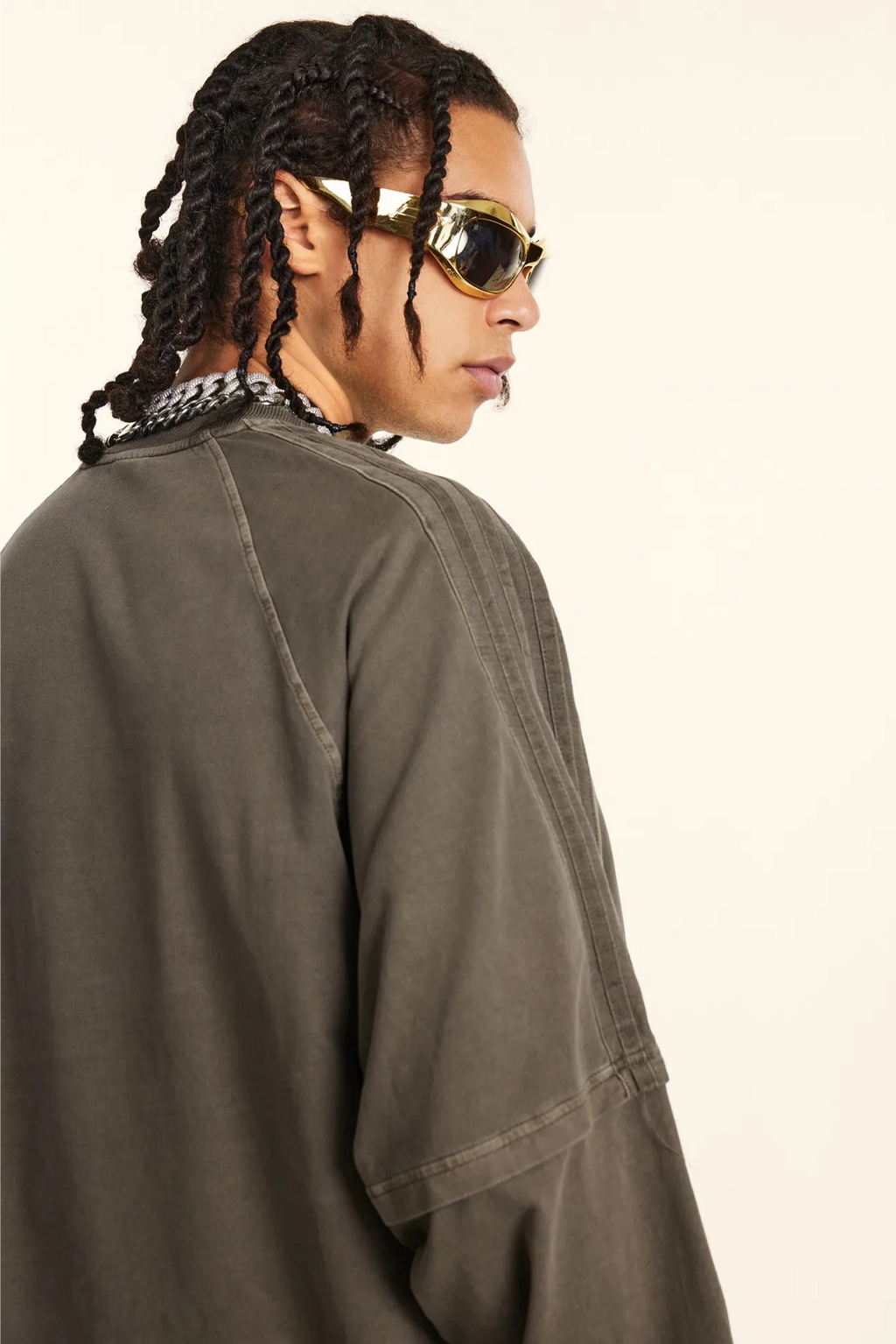 Person wearing a green jacket and gold sunglasses on a white background