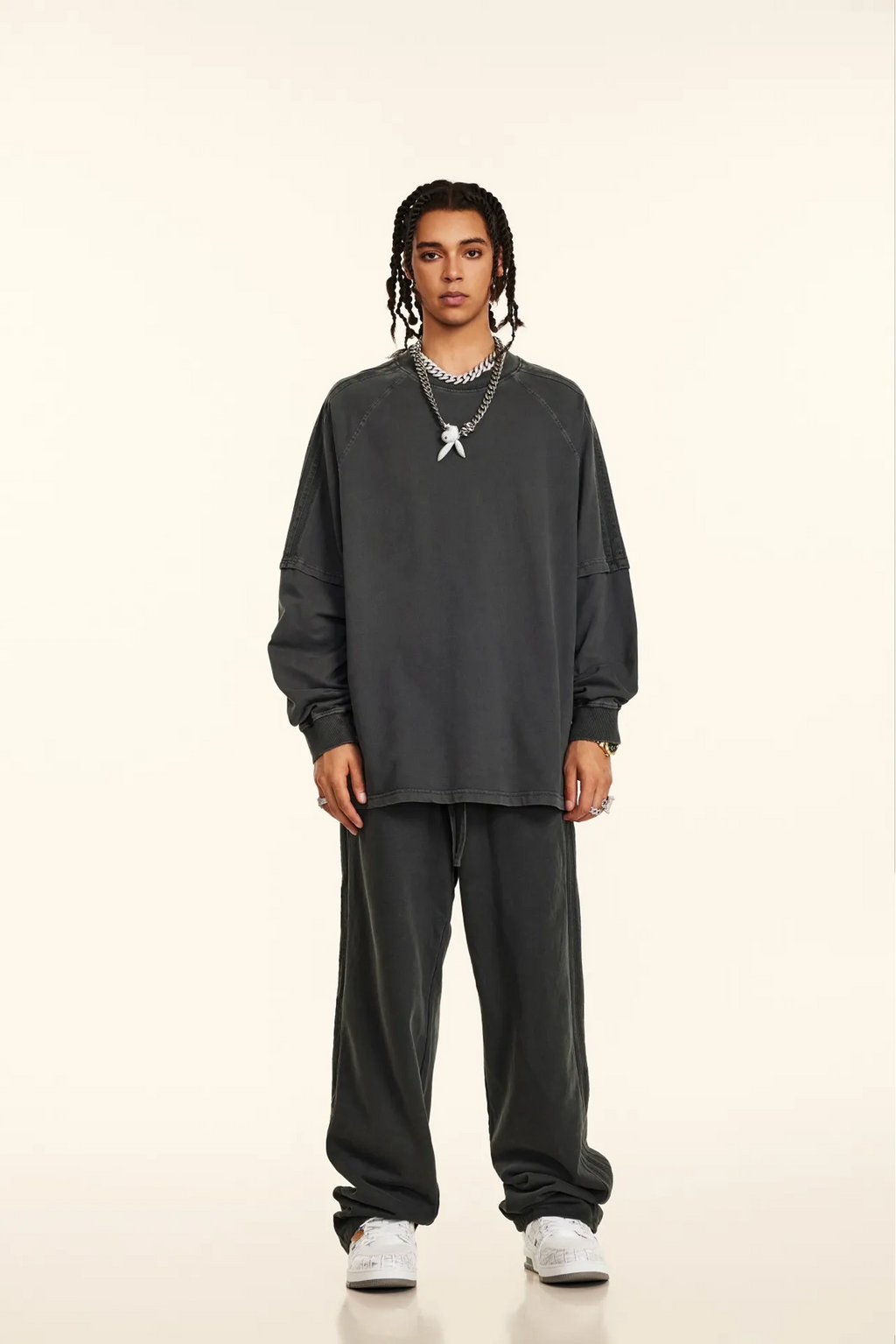 Person wearing a dark gray sweatshirt and pants on a white background