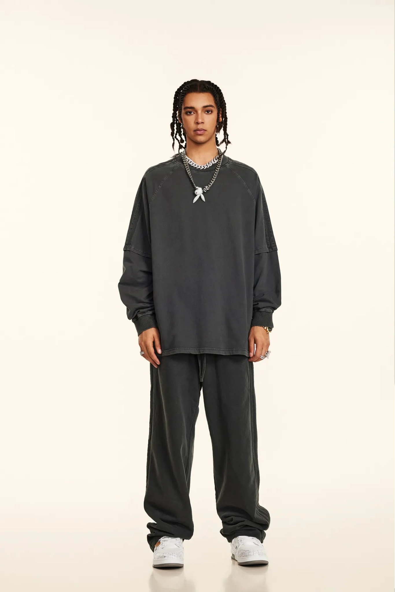 Person wearing a dark gray sweatshirt and pants on a white background