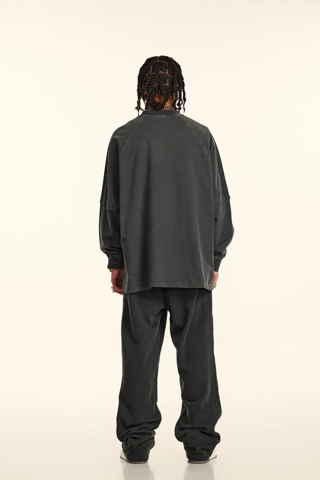 Person wearing a dark gray outfit on a white background