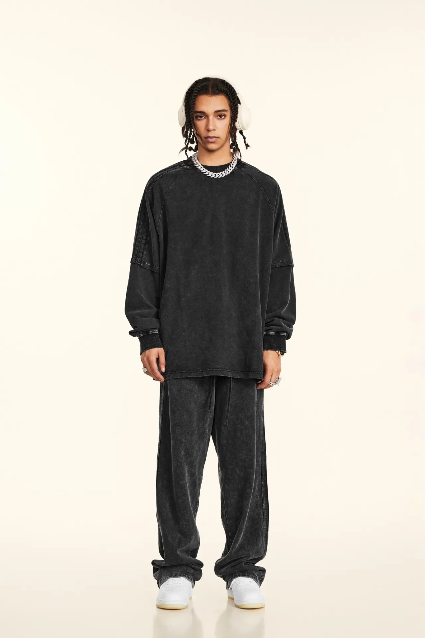 Person wearing a black oversized sweatshirt and pants on a beige background