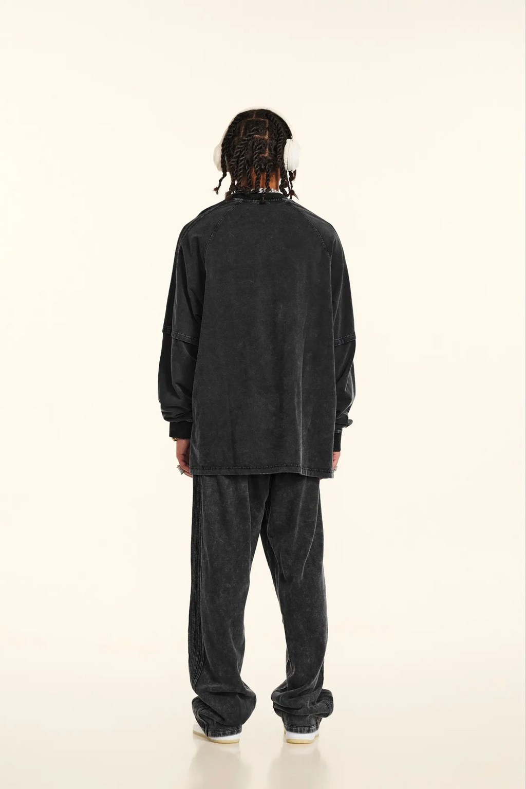 Person wearing a black long-sleeve shirt and pants on a white background