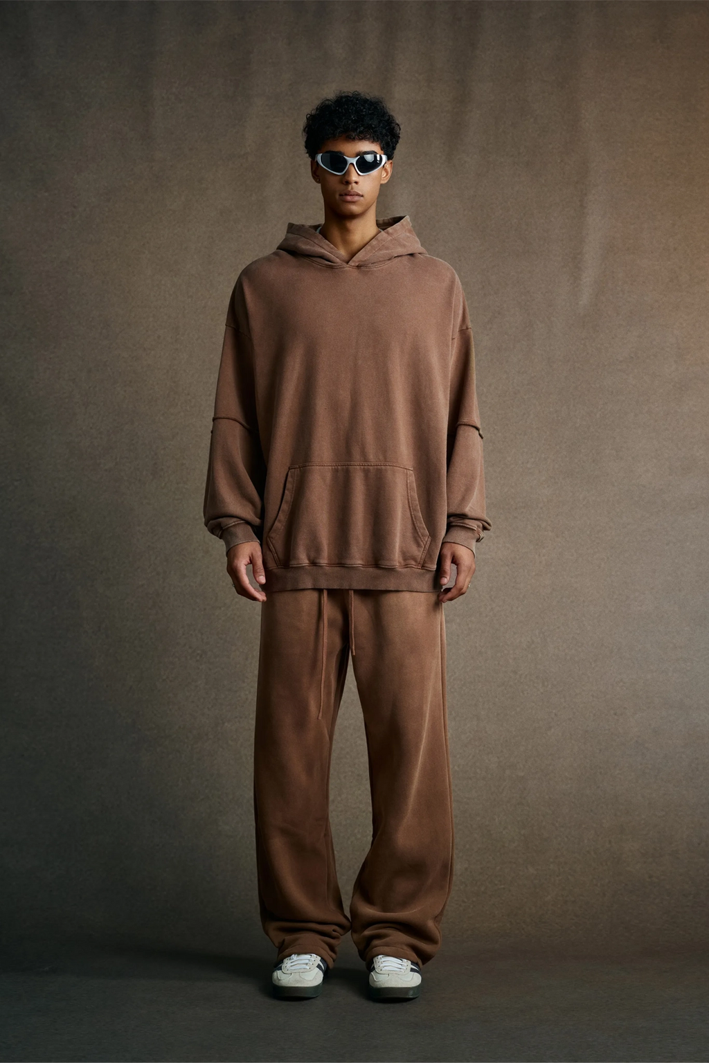 Person wearing a brown hoodie and pants set against a plain background