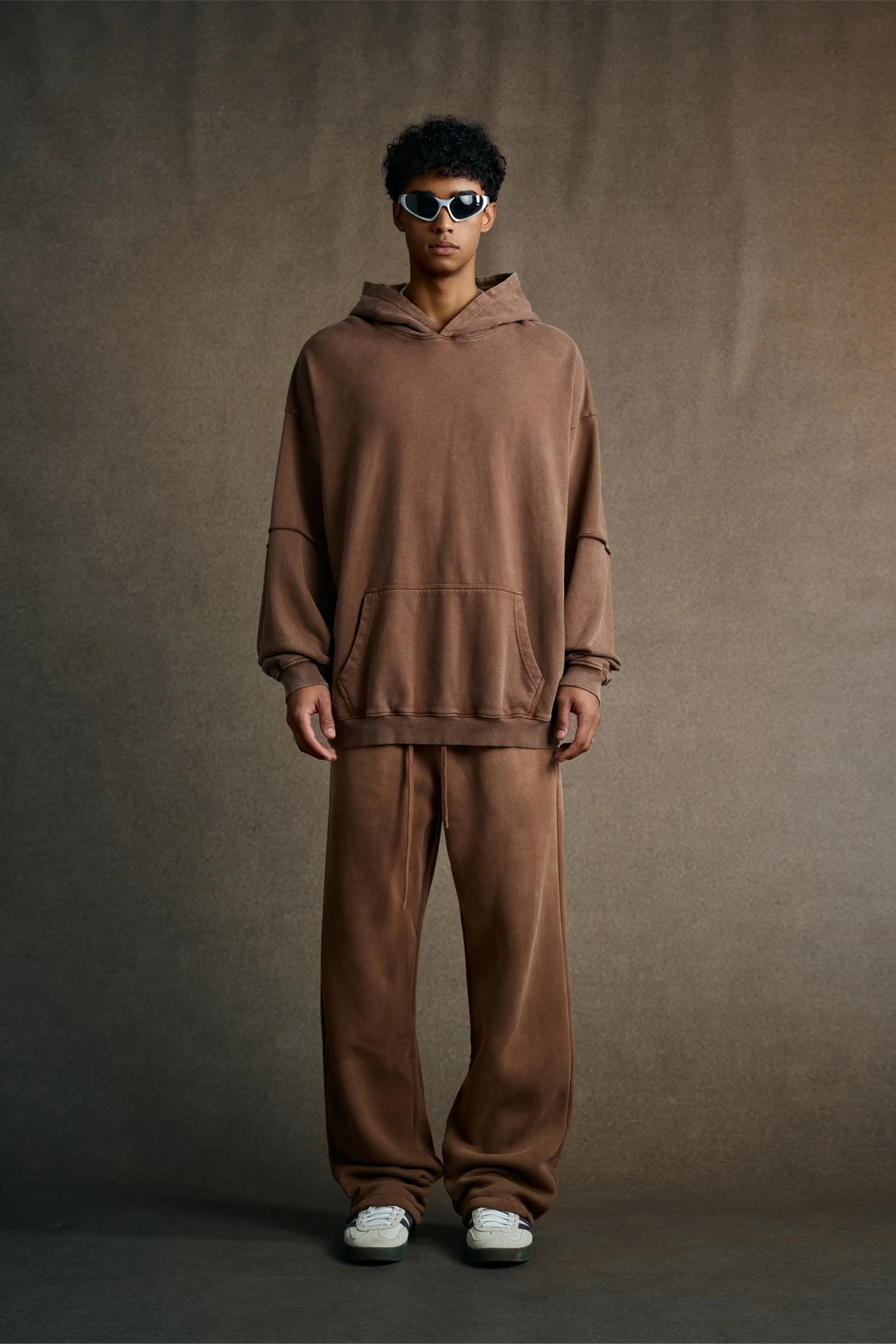 Person wearing a brown hoodie and pants set against a plain background
