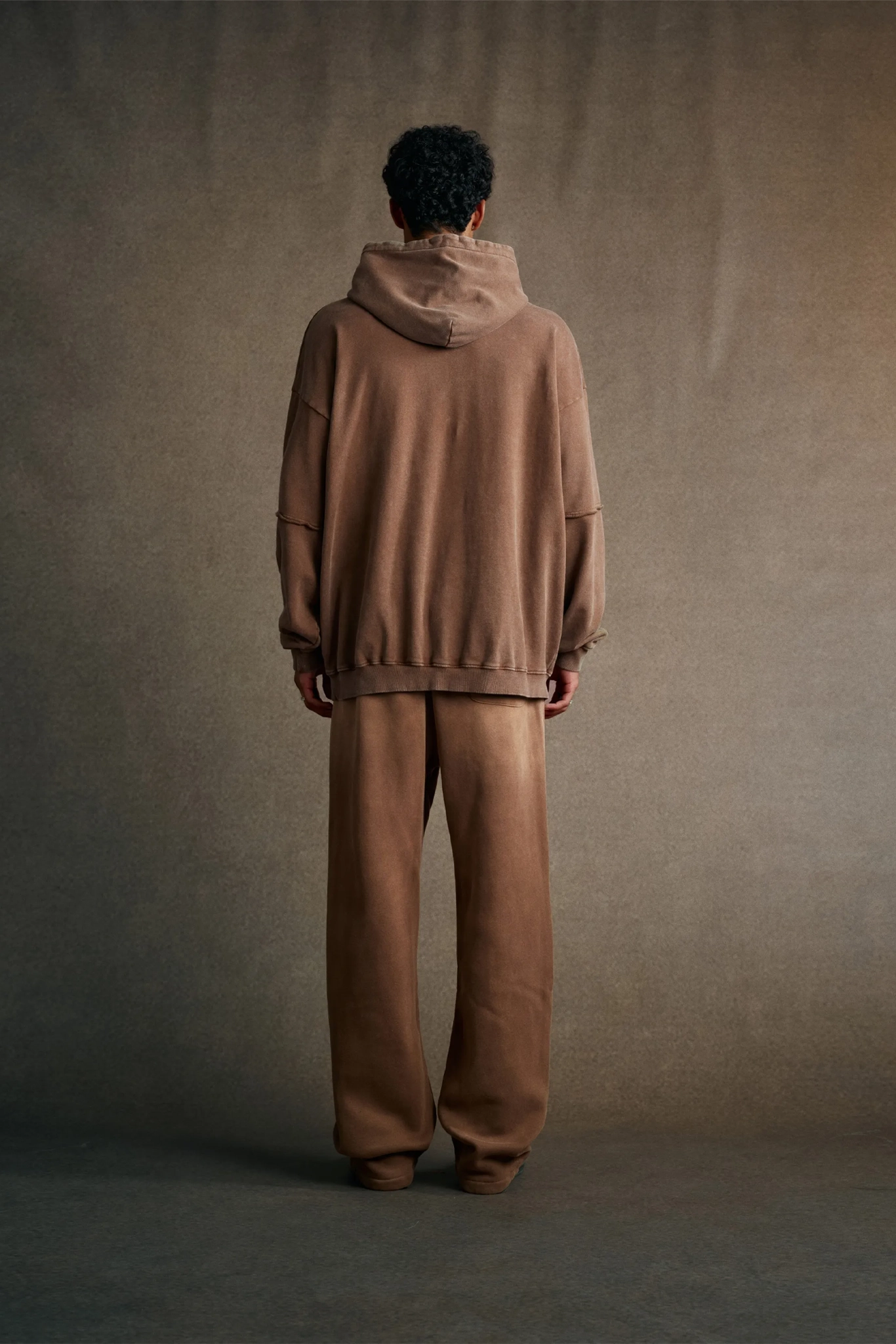 Person wearing a brown tracksuit standing against a plain background