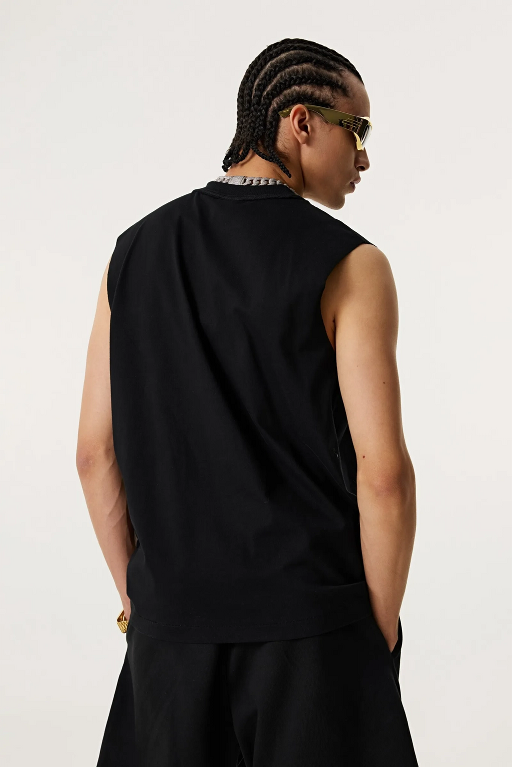 Person wearing a black sleeveless top and pants against a white background