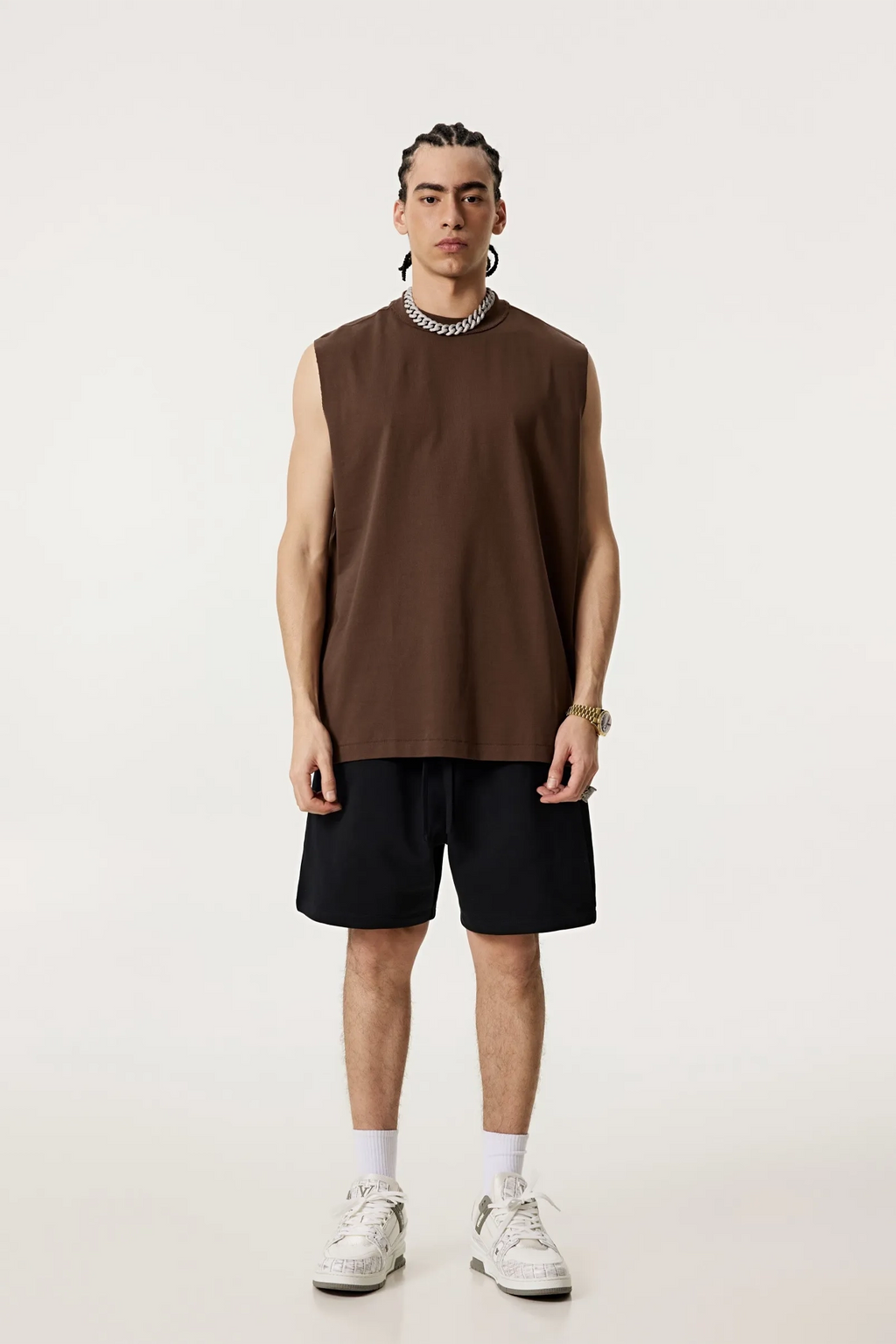 Person wearing a brown sleeveless shirt and black shorts on a white background