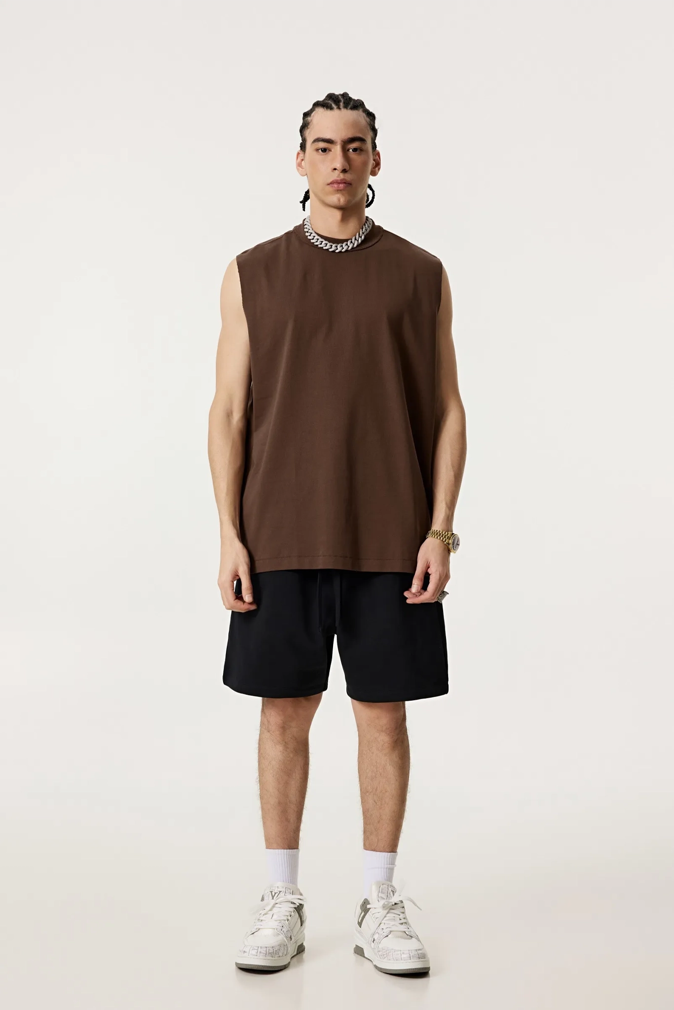 Person wearing a brown sleeveless shirt and black shorts on a white background