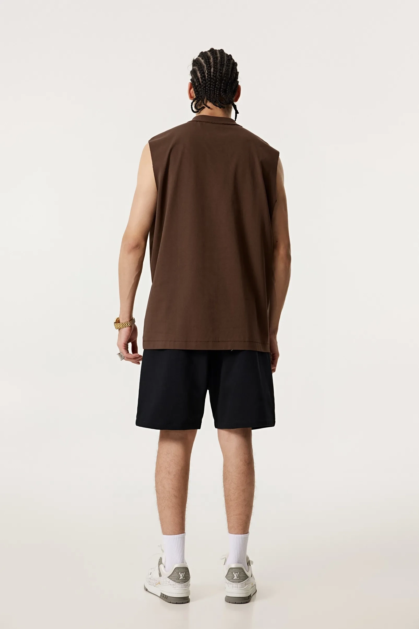 Person wearing a brown sleeveless shirt and black shorts on a white background