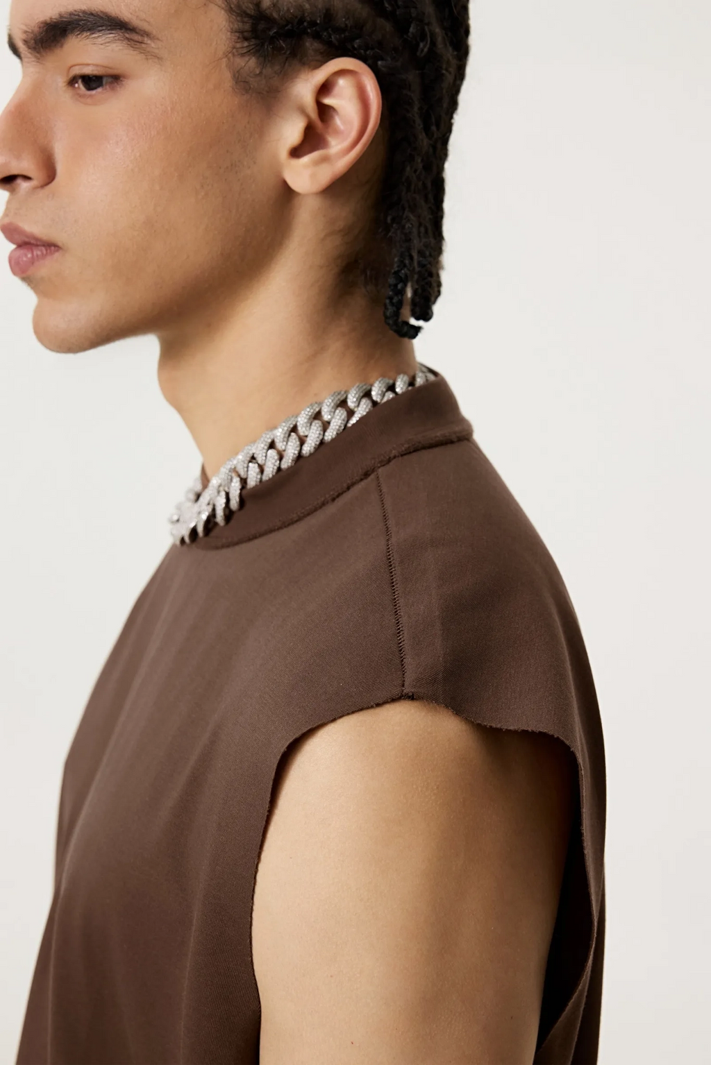 Person wearing a brown sleeveless top with a decorative collar against a white background