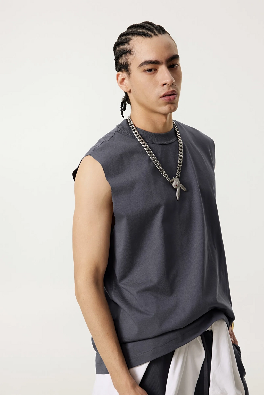 Man wearing a sleeveless gray top with a white skirt on a plain background