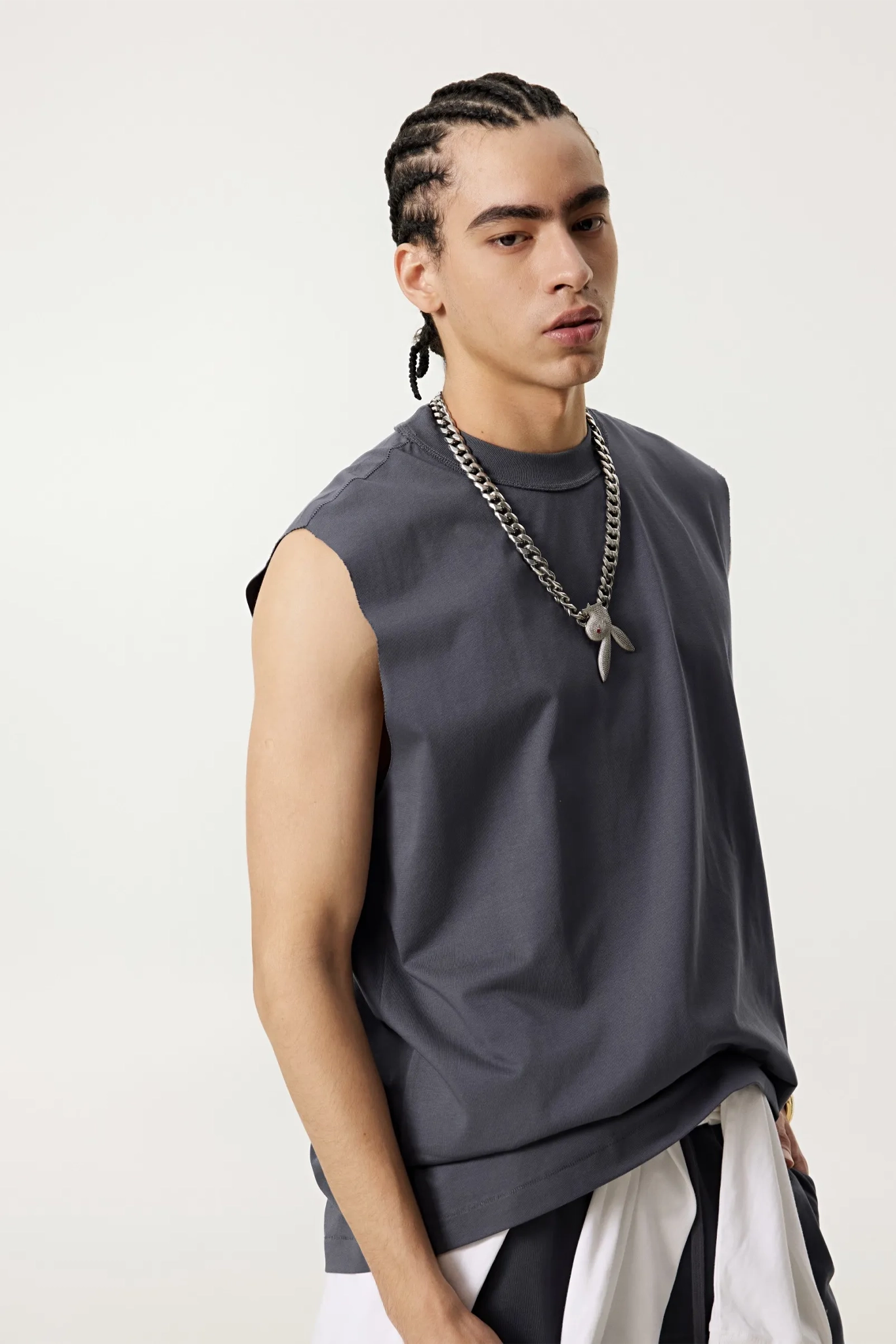 Man wearing a sleeveless gray top with a white skirt on a plain background