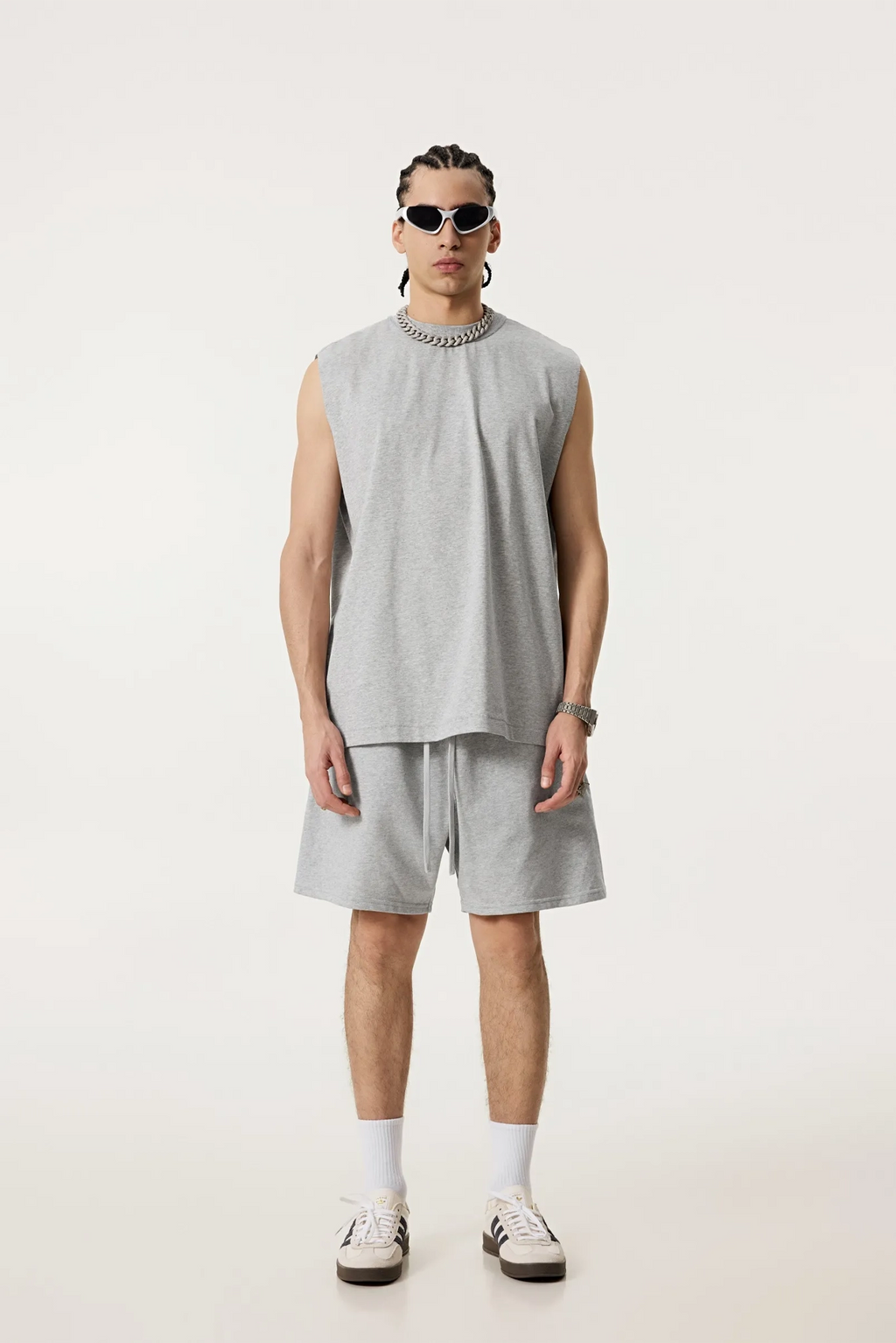 Person wearing a sleeveless gray top and shorts on a white background