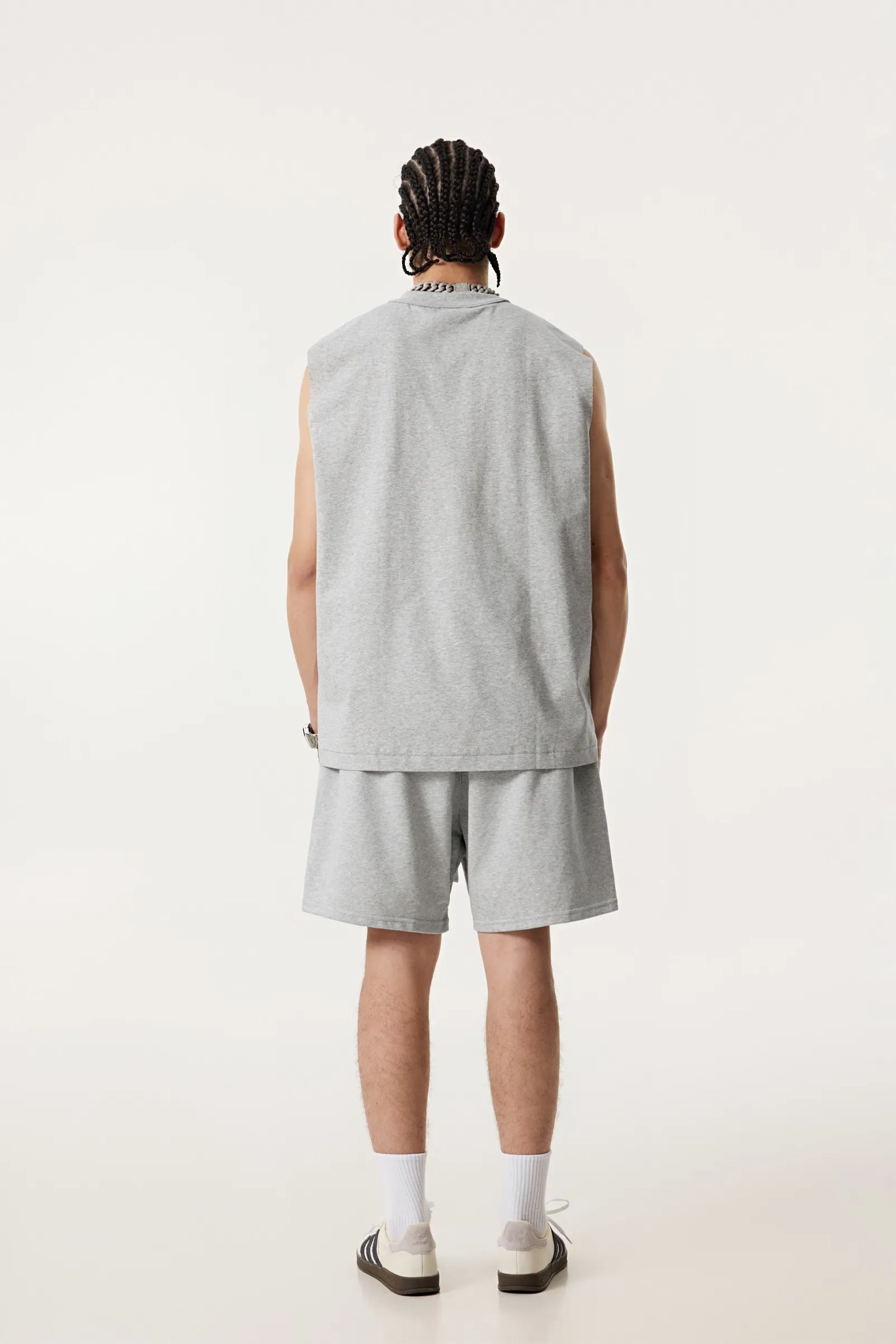 Person wearing a gray sleeveless shirt and shorts set on a white background