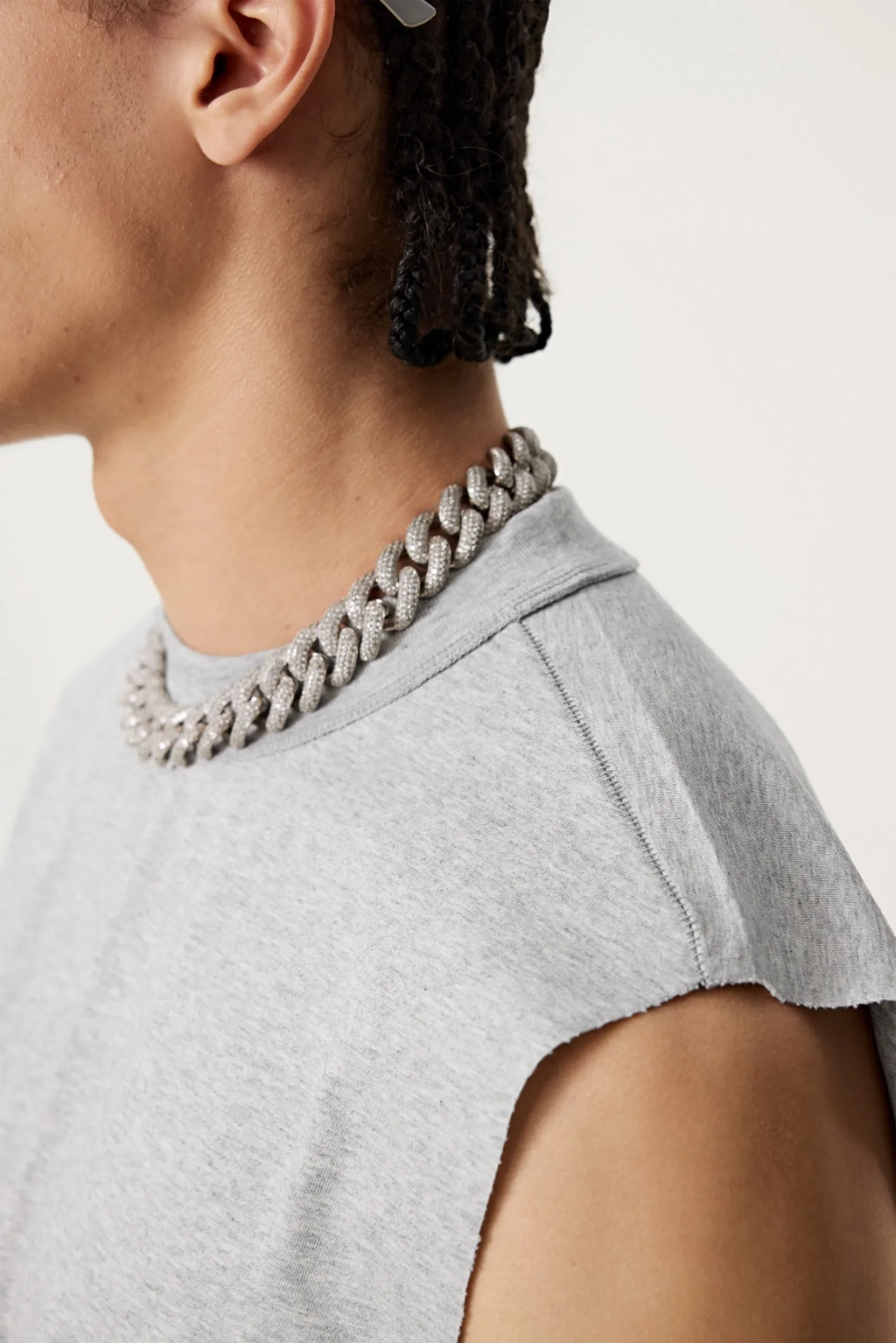 Person wearing a gray chain necklace and gray top on a light background