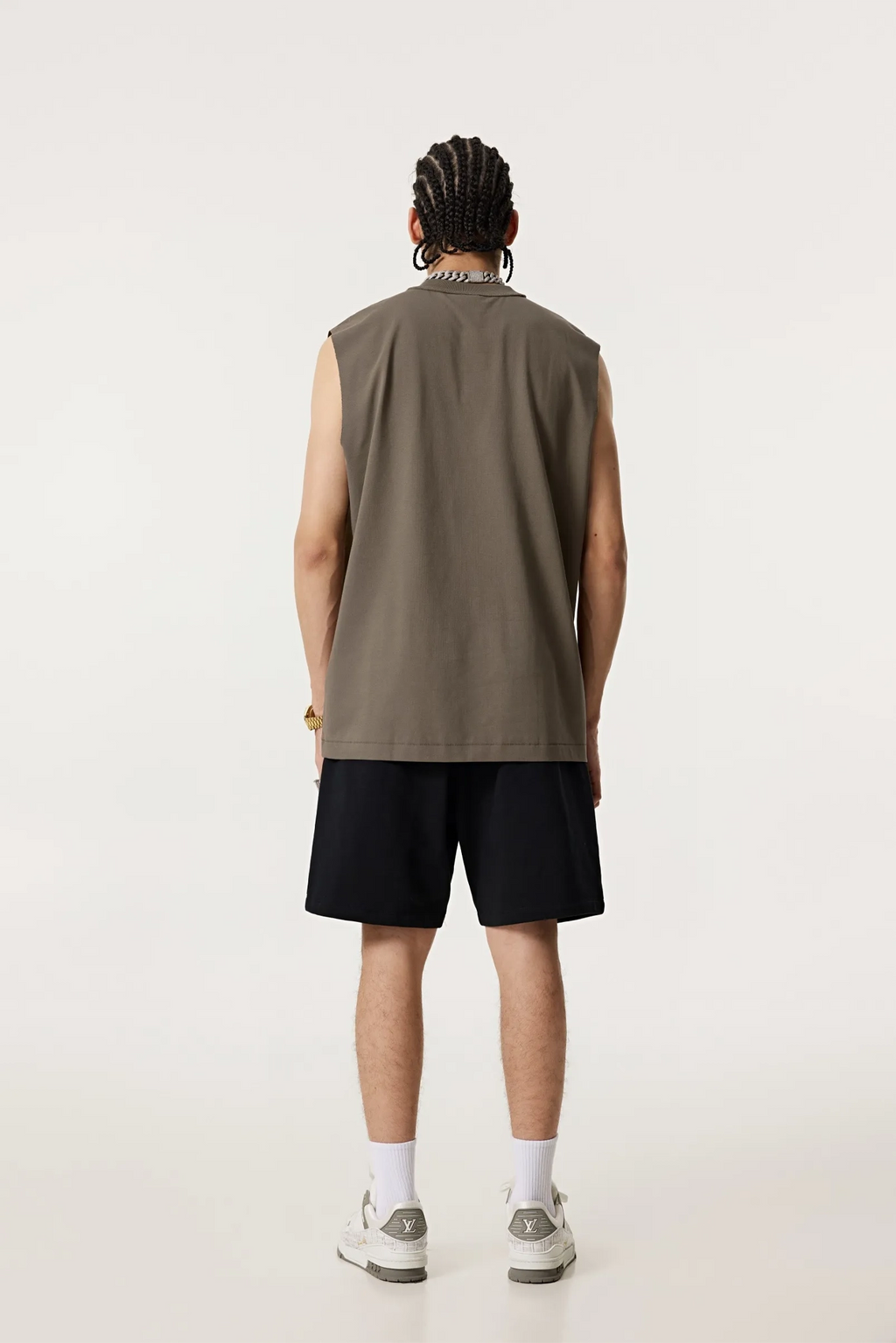 Person wearing a sleeveless brown shirt and black shorts on a white background