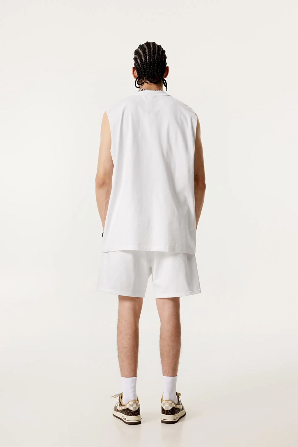 Person wearing a white sleeveless shirt and shorts set on a white background