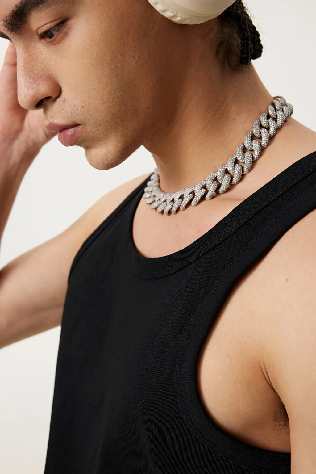 Man wearing a black tank top and silver chain necklace against a plain background